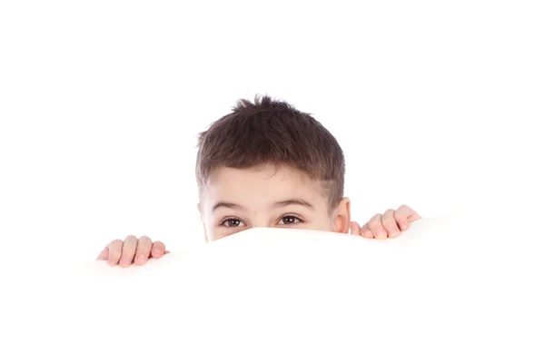 Ung pojke gömmer sig bakom en skylt och att göra ett ansikte isolerad på vit bakgrund — Stockfoto