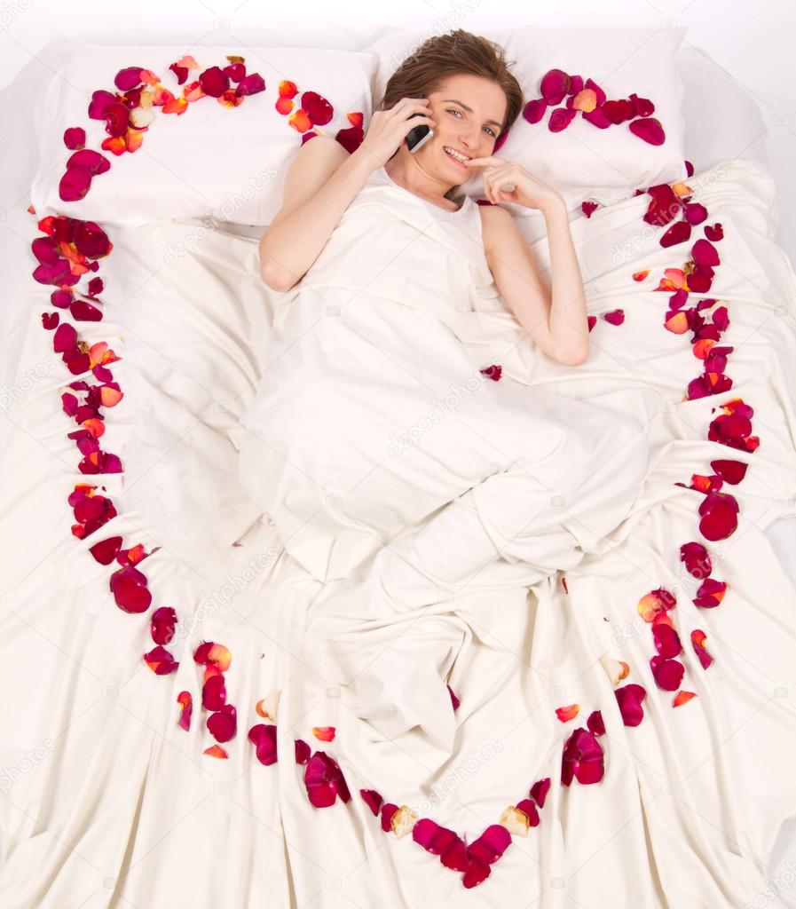 Woman lieing in bed covered by Flower Petals