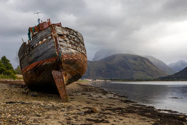 这艘船在苏格兰高地的威廉堡附近撞毁了以本 尼维斯为背景的卡尔老船 — 图库照片
