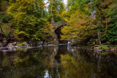 Dunkeld, İskoçya - 11 Ekim 2021: İskoçya 'nın Dunkeld kentindeki Hermitage ormanında Braan Nehri üzerindeki eski bir taş köprünün manzarası.