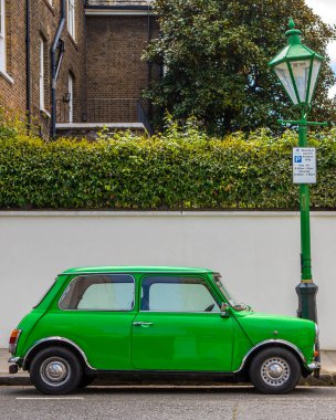 Londra, İngiltere - 5 Mayıs 2022: Yeşil bir Mini Cooper Londra 'nın Kensington bölgesinde yeşil bir lambanın yanına park etti..