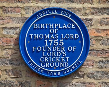 Thirsk, UK - June 7th 2022: A blue plaque on the exterior of Thirsk Museum, marking were Thomas Lord, founder of Lords Cricket Ground, was born in 1755.