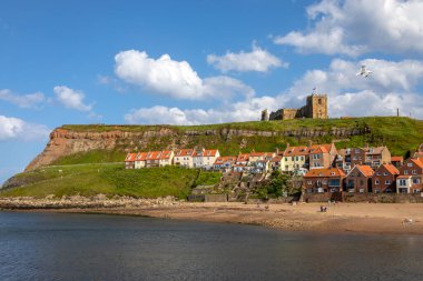 Kuzey Yorkshire, İngiltere 'nin güzel sahil kasabası Whitby' deki Doğu Kayalıkları manzarası. St. Mary Kilisesi uçurumun tepesine tünemiştir..