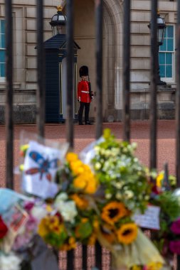 Londra, İngiltere - 9 Eylül 2022: Kraliyet Muhafızları ve çiçekler bir önceki gün ölen Kraliçe II. Elizabeth 'in anısına Londra, İngiltere' deki Buckingham Sarayı 'nda.