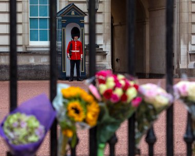 Londra, İngiltere - 9 Eylül 2022: Kraliyet Muhafızları ve çiçekler bir önceki gün ölen Kraliçe II. Elizabeth 'in anısına Londra, İngiltere' deki Buckingham Sarayı 'nda.