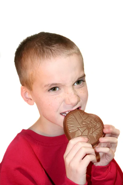 Intens jongen bijten chocolade hart 1 — Stockfoto