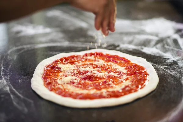 Sprinkling cheese on home made pizza — Stock Photo, Image