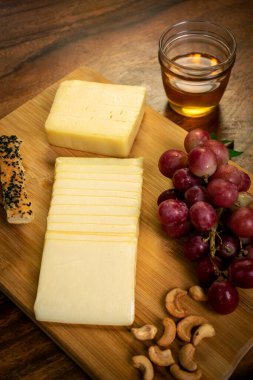 Tahtada dilimlenmiş çedar peyniri, üzümlü, fındıklı, ekmekli ve ballı.