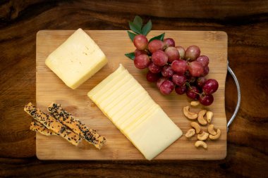 Tahtada dilimlenmiş çedar peyniri, üzümlü, fındıklı, ekmekli ve ballı.