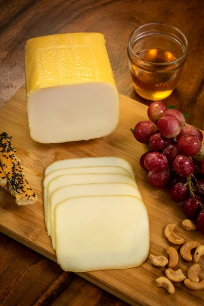 木の板の上でモッツァレラチーズのブロックを燻製にしたブドウ カシューナッツ パンスティック — ストック写真