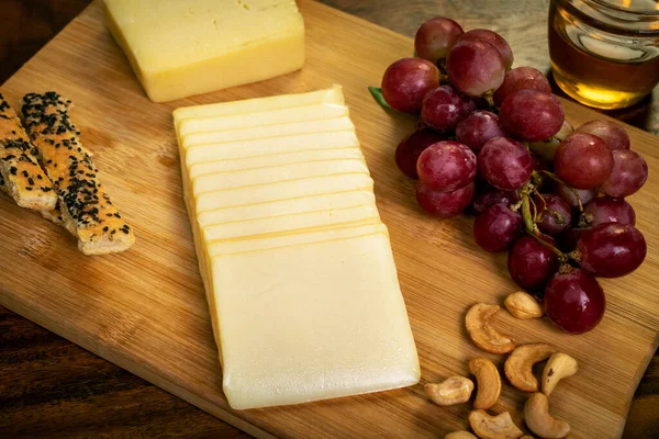 Tahtada dilimlenmiş çedar peyniri, üzümlü, fındıklı, ekmekli ve ballı.