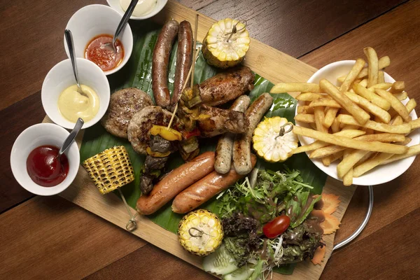 Köfte, sosis, şiş ve ahşap arka planda tavuk kanadı ile karışık et tabağı.