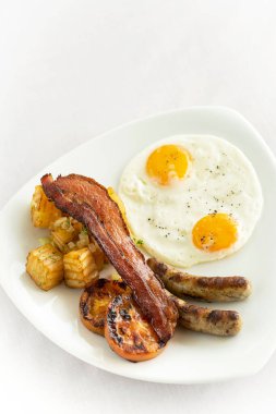 Avustralya kahvaltısı, sahanda yumurta, sosis, pastırma ve patates.