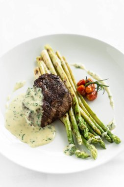 grilled filet mignon tenderloin steak with asparagus and creamy dill sauce on white background