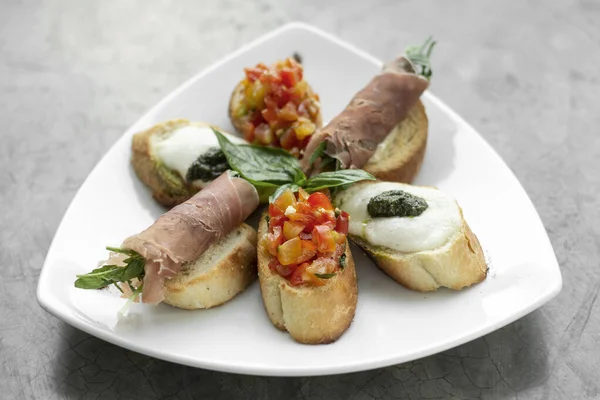 Parma jambonu, bruschetta ve mozarella sosuyla karışık crostini aperatifleri.