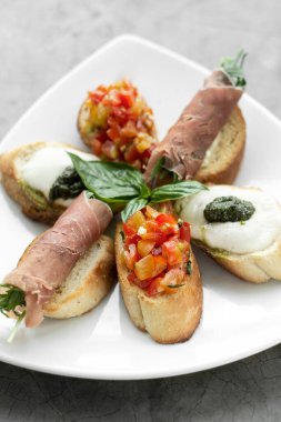 Parma jambonu, bruschetta ve mozarella sosuyla karışık crostini aperatifleri.