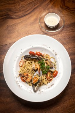 Framti di mare ahşap masa arkasında taze karışık deniz ürünleri spagettisi.