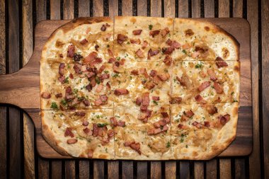 Flammkuchen tarte flambee rectangular pizza with bacon and chicken on wood table background