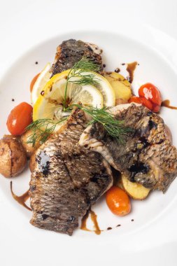 Beyaz arka planda patates ve sebzeli taze levrek fileto.