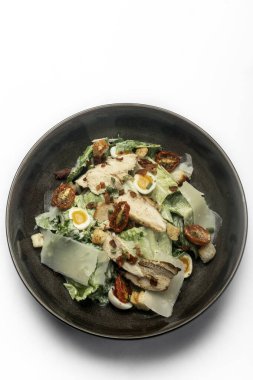 fresh chicken caesar salad in bowl on white background