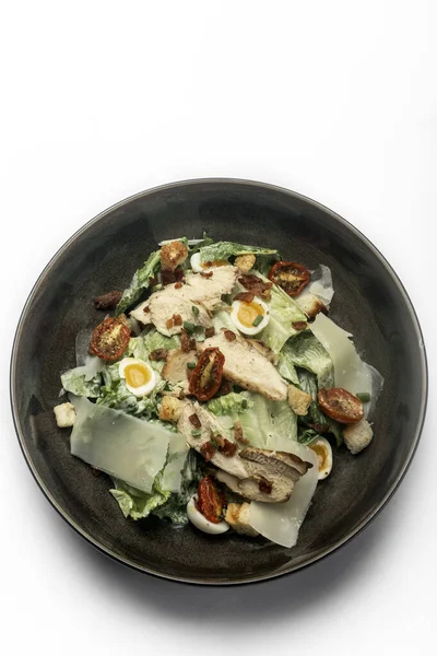 fresh chicken caesar salad in bowl on white background