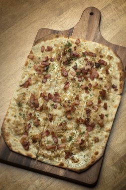 Flammkuchen tarte flambee rectangular pizza with bacon and chicken on wood table background