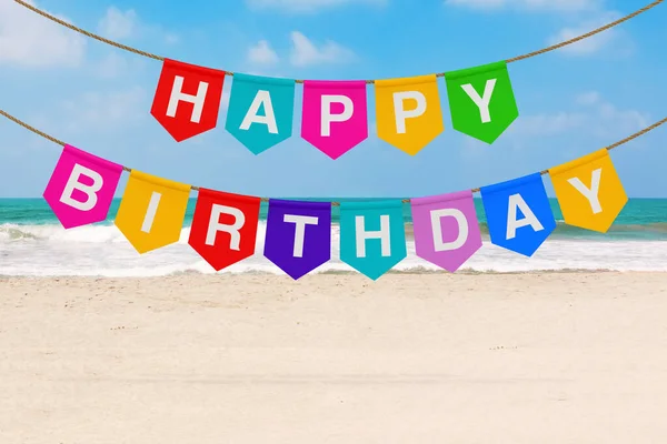 Hanging Multicolor Party Fags Banner with Happy Birthday Sign on a sea or ocean sand beach background. 3d Rendering