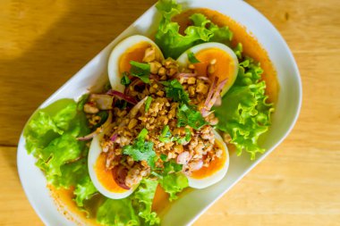 Baharatlı salata ve ahşap masada kaynamış yumurta.