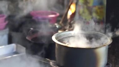 Sıcak erişte tenceresinin üzerinde paslanmaz çelik süzgeç. Akitchen 'de kaynayan buhardan beyaz duman çıkıyor. Tayland sokak yemekleri.