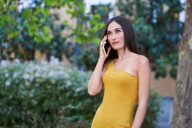 Bahçe bölgesinde akıllı telefondan konuşan genç bir kadın...