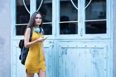 Sırt çantalı, kulaklıklı, güzel bir genç kadın.