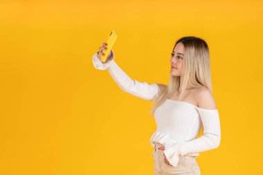 Genç bir kadın akıllı telefonuyla selfie çekiyor. Stüdyo fotoğrafçılık