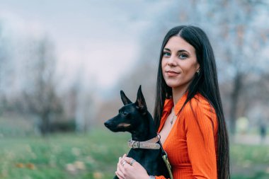 Köpeğiyle esmer bir kadın, şefkatli bir jestle. Kavram, köpek ve evcil hayvan sevgisi