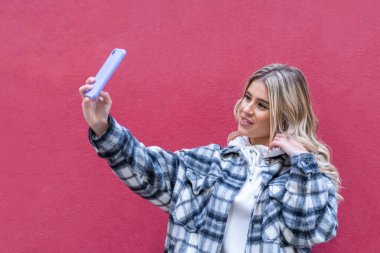 Pembe arka planda kalın giysili genç sarışının ön görüntüsü