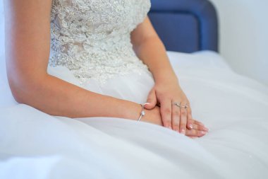 Beyaz dantelli gelinlikte manikürlü gelin elleri. Kucağındaki gelinin elini kapat. Gelinin elleri gelinlik içinde