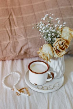 Yatağında kahve fincanı olan bir vazoda kurumuş çiçeklerle dolu bir buket hayat. Sabah kadınsı kavram