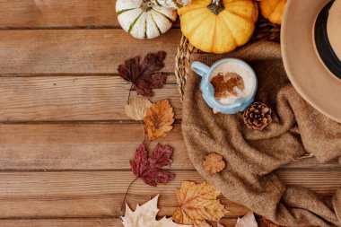 Sonbahar sonbahar kompozisyonu. Tahta masa, sıcak süveter, sıcak kahve, şapka ve balkabağı. Düz yerde, üst tarafta. İskandinav, higge, konforlu ev kavramı