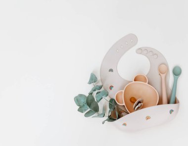 Bebek beslenme aksesuarları. Silikon önlük, bulaşık takımı. Düz konum, üst görünüm, kopyalama alanı.