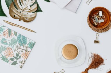 Blogger çalışma alanı dümdüz uzanıyordu. İçinde tropik canavar yaprağı, kahve, malzeme, defter ve kalem olan ofis masası. Düz konum, üst görünüm, kopyalama alanı