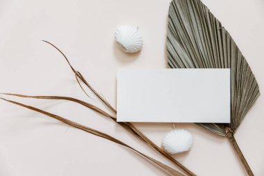 Yaz kırtasiyesi en az model. Boş kart, palmiye yaprakları, bej desenli masa arkaplanı. Düğün maketi. Düz yatış, üst görünüm