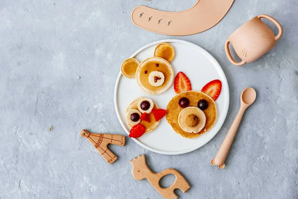 Funny food for kids. Bear and cat made of pancakes with strawberries. Idea for a baby breakfast. Top view, flat lay