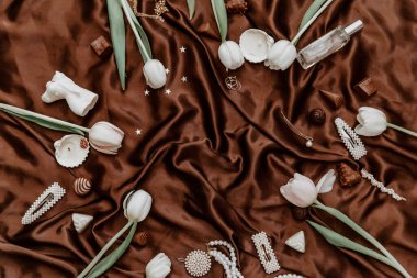 Kadın aksesuarları, beyaz laleler ve mumlar düzdü. Moda blogu, web, sosyal medya için yaratıcı kompozisyon. Üst görünüm