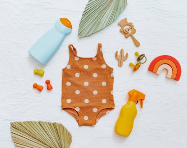 Bebek mayosu, plaj aksesuarları ve güneş kremi. Çocuklar için güneş losyonu. Ultraviyole koruma ürünü kavramı, yaz çocukları kozmetik ürünleri.