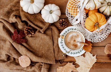 Sonbahar sonbahar kompozisyonu. Tahta masa, sıcak süveter, sıcak kahve, şapka ve balkabağı. Düz yerde, üst tarafta. İskandinav, higge, konforlu ev kavramı