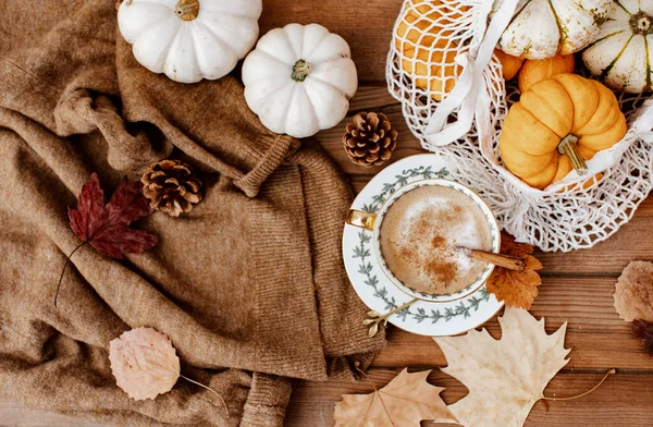 Sonbahar sonbahar kompozisyonu. Tahta masa, sıcak süveter, sıcak kahve, şapka ve balkabağı. Düz yerde, üst tarafta. İskandinav, higge, konforlu ev kavramı