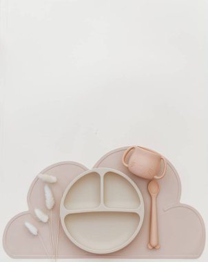 Set of tableware and silicone bibs. Baby accessories. Kids nutrition and feeding concept. Top view, flat lay