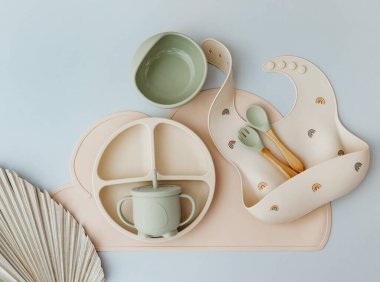 Mavi ışık arka planında silikon bulaşık takımı ve bebek aksesuarları, düz uzanma