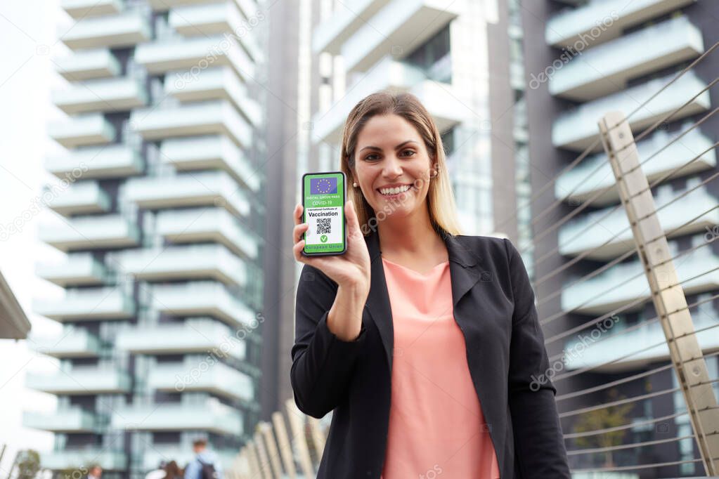 Woman holding a smartphone with a Green Pass. The Green Pass facilitate the safe free movement within the EU during the COVID-19 pandemic.
