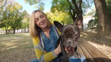 Sonbaharda Fransız Bulldog 'u olan mutlu genç bir kadın.