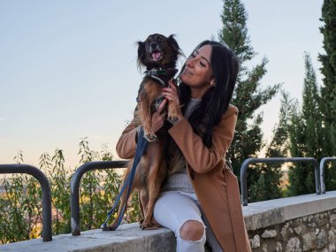 Esmer kadın küçük köpekle oynuyor.